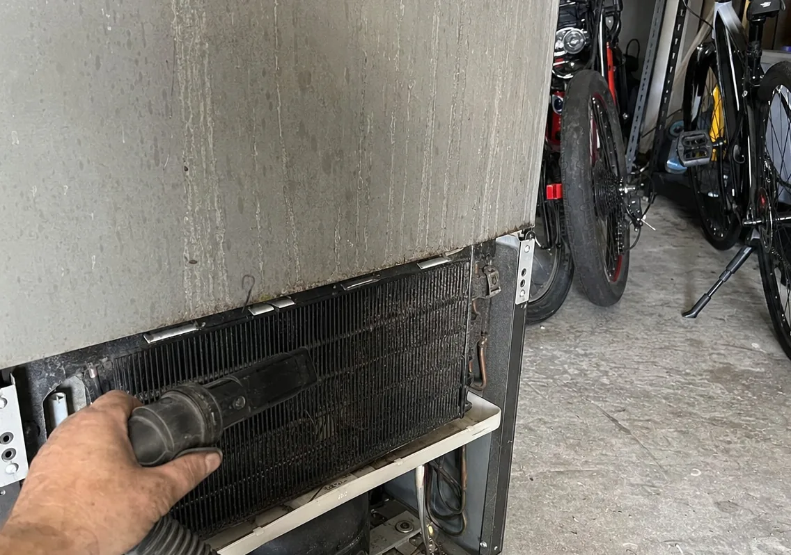 Bicycles and storage bins crowded against a refrigerator that has to draw its condenser air from the same few inches.