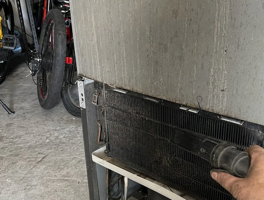 A condenser coil packed with dust and lint, photographed close enough to see the spacing of the fins.